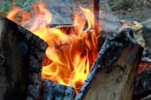 A roaring log campfire with yellow and orange flames