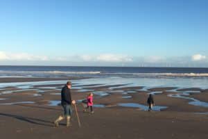 Children walking on deserted Chapel Six Marshes beach wrapped up in winter coats