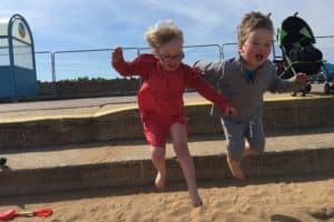 Twins jumping from the steps on Skegness Promenade into the golden sand
